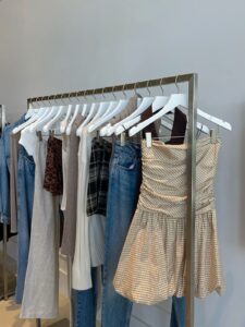 boutique clothing rack with neutral blouses, dresses, and soft pastel pieces displayed in a minimal store