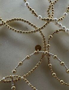 close-up of gold beaded bracelets with pearl accents arranged on a neutral background